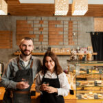 couple-aprons-posing-with-cups-coffee