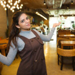happy-female-small-business-owner-showing-her-cafe